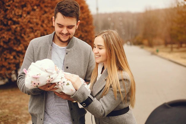 A heartwarming scene of a couple holding their newborn baby and sharing joyful smiles. The couple is shown in a cozy and loving embrace, with the father cradling the baby in her arms and the mother gently supporting them removes away stress.