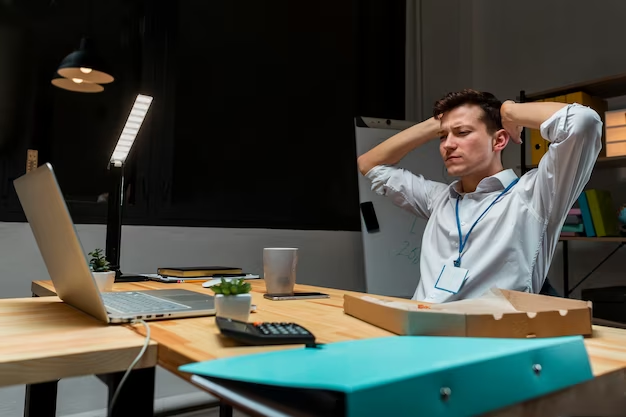 A young individual working & stressed overnight in his office, considering themselves a solopreneur. The person is depicted diligently working at their desk, surrounded by the tools and equipment necessary for their business activities.