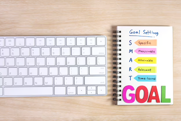 A picture featuring the keyword in the image, there is a diary open to a page labeled 'Goal Setting,' with the acronym SMART written on it. 