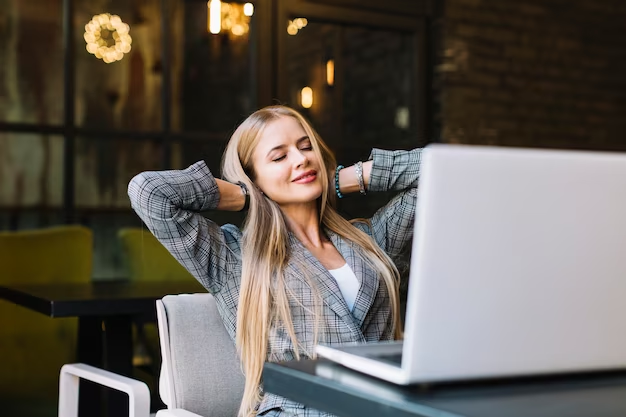 A beautiful girl sitting on a chair, with her eyes closed and a laptop placed in front of her. She is in a state of relaxation, displaying a peaceful expression. The image represents the concept of taking a break to foster a positive mindset.